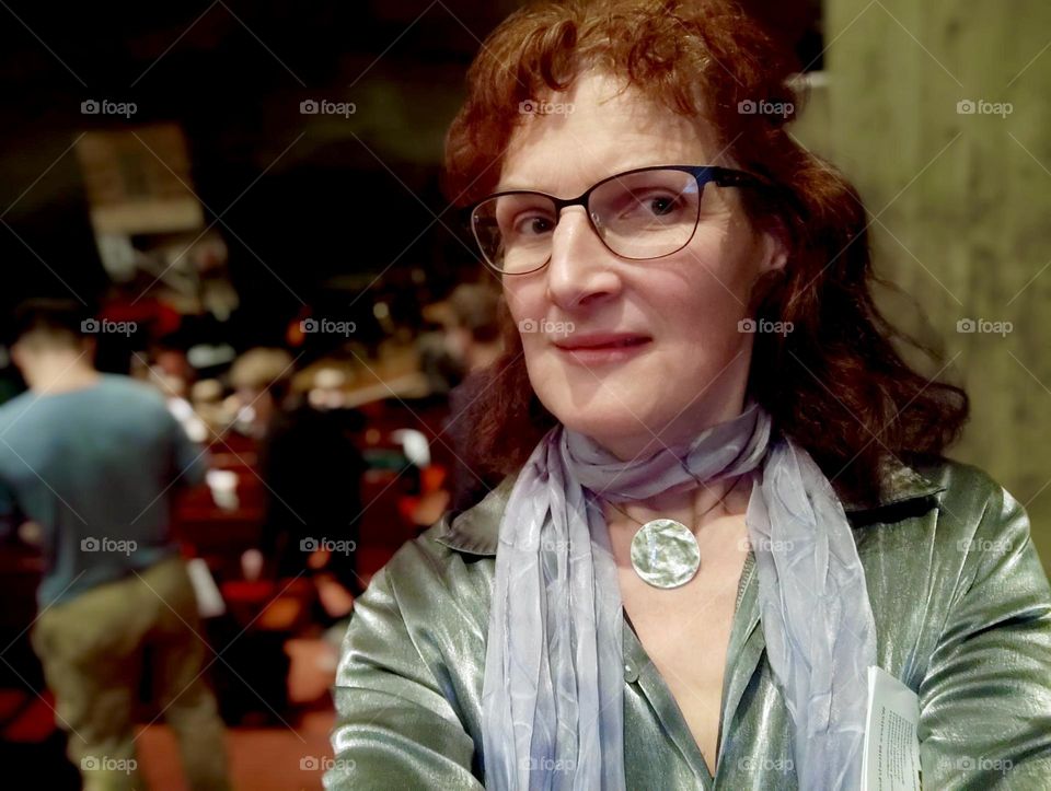 The lovely lady dressed in a metallic silver top, scarf and matching silver pendant is a special guest at the musical “West Side Story” performed by students in “Regensburg” at the music academy. 2024. Hypnotic Productions
