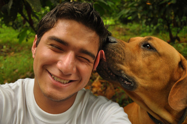 Selfie of a dog licking the face of a young man 
