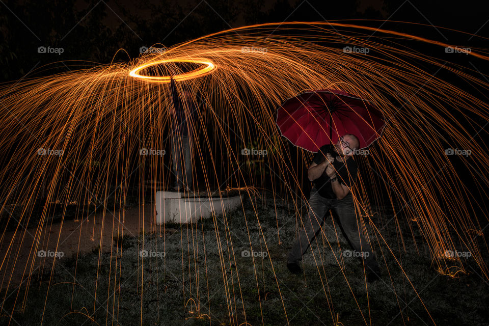 Man holding umbrella below a spinning steel wool