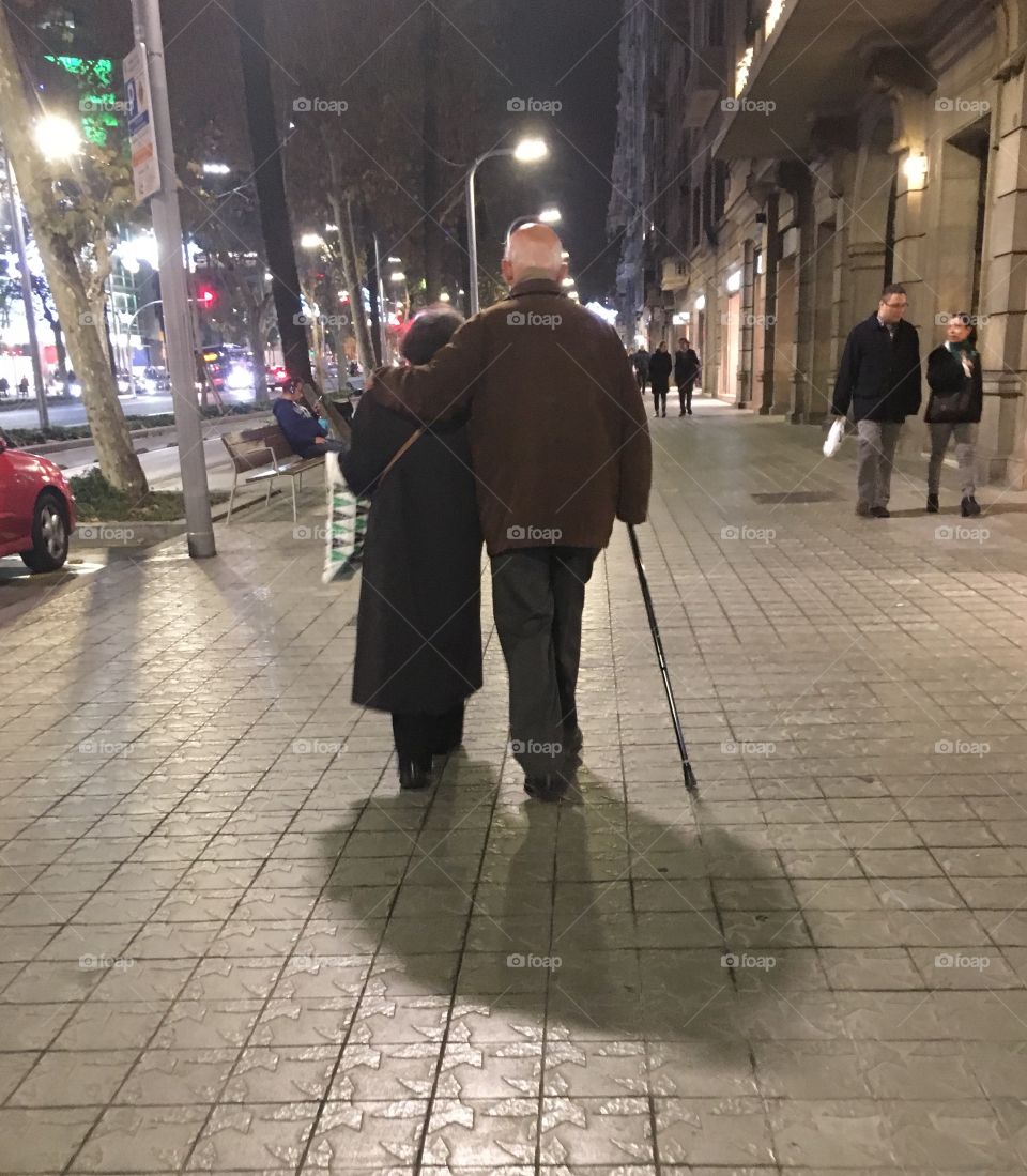 Elderly couple taking a stroll down the avenue on a crisp December evening.