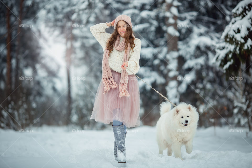 Beautiful woman with dog samoyed in winter forest