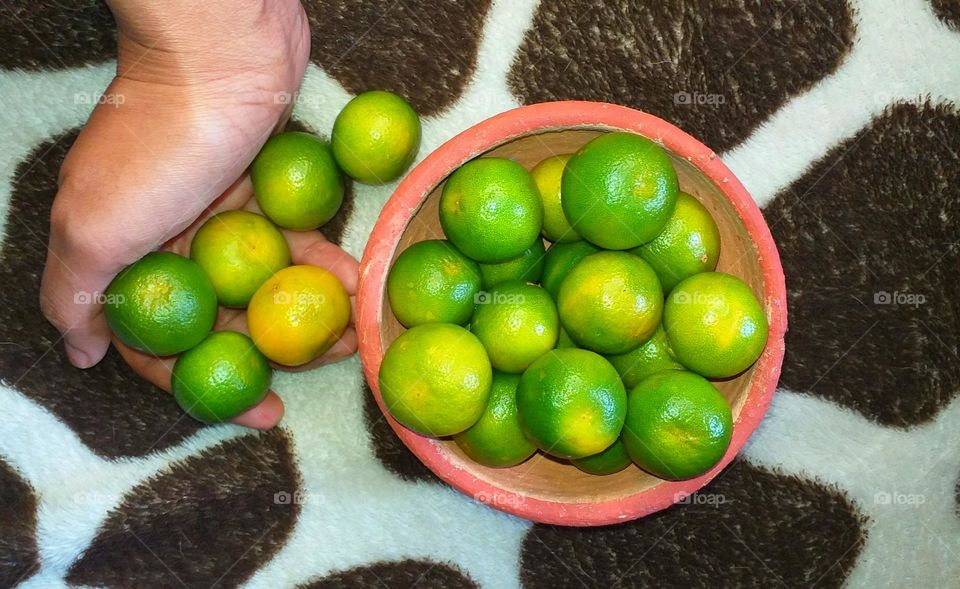 Oranges in a hand and a clay bowl - summer treats