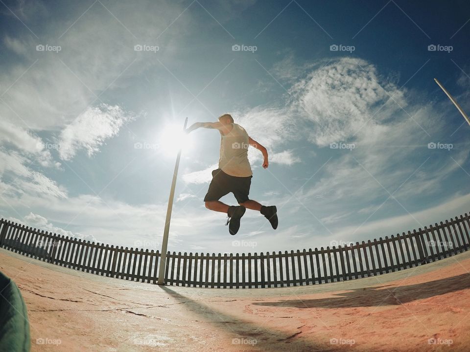 Man jumping in mid-air against cloudy sky