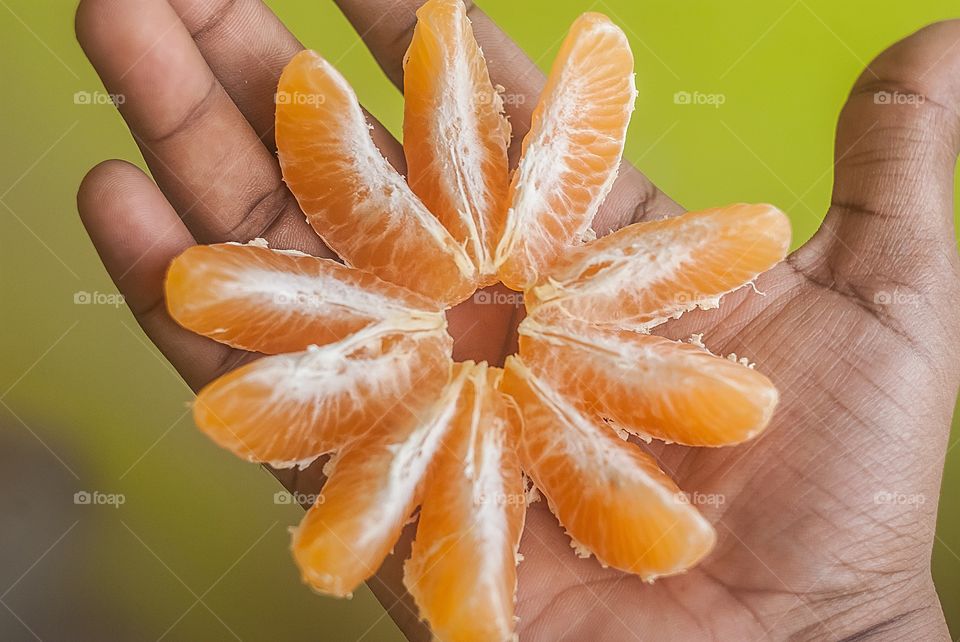 A person holding orange slice on hand