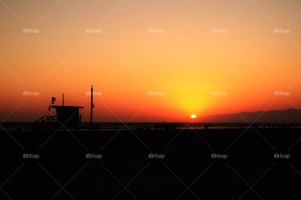 sunset over mountains, and shilouette of the lifeguard on beach