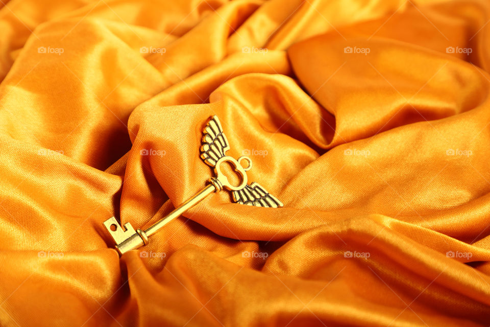 Antique golden key on a good colored satin fabric