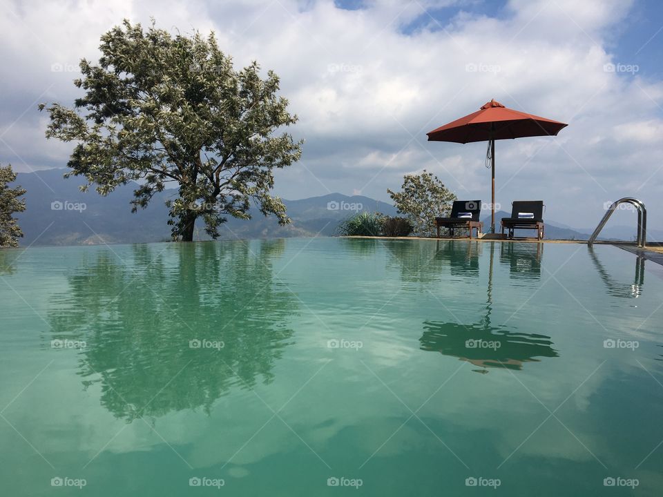 Infinity pool with chairs and tree in the mountains 
