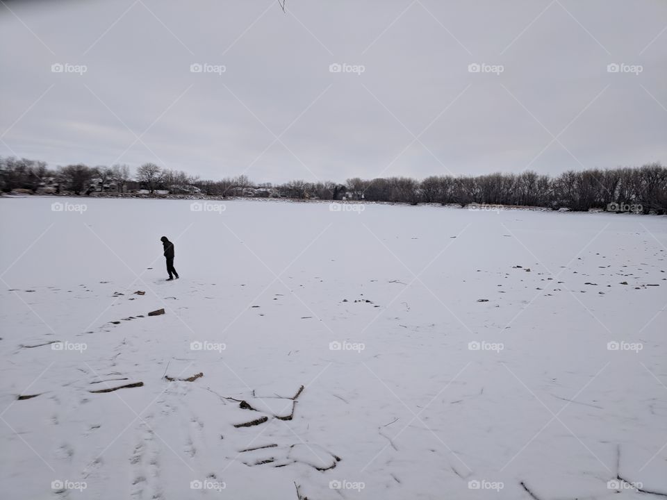 man walks on frozen reservoir