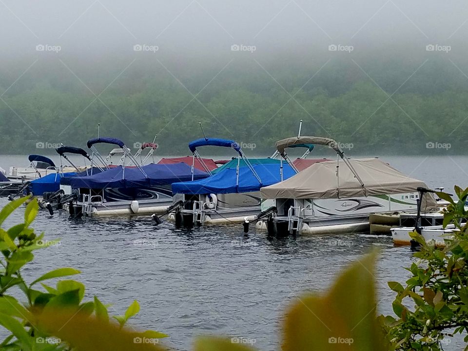 marina of colorful boat covers on foggy mountain lake in morning