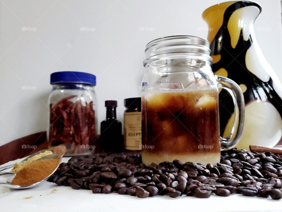 Cold brew coffee surrounded by Coffee beans and add in ingredients.