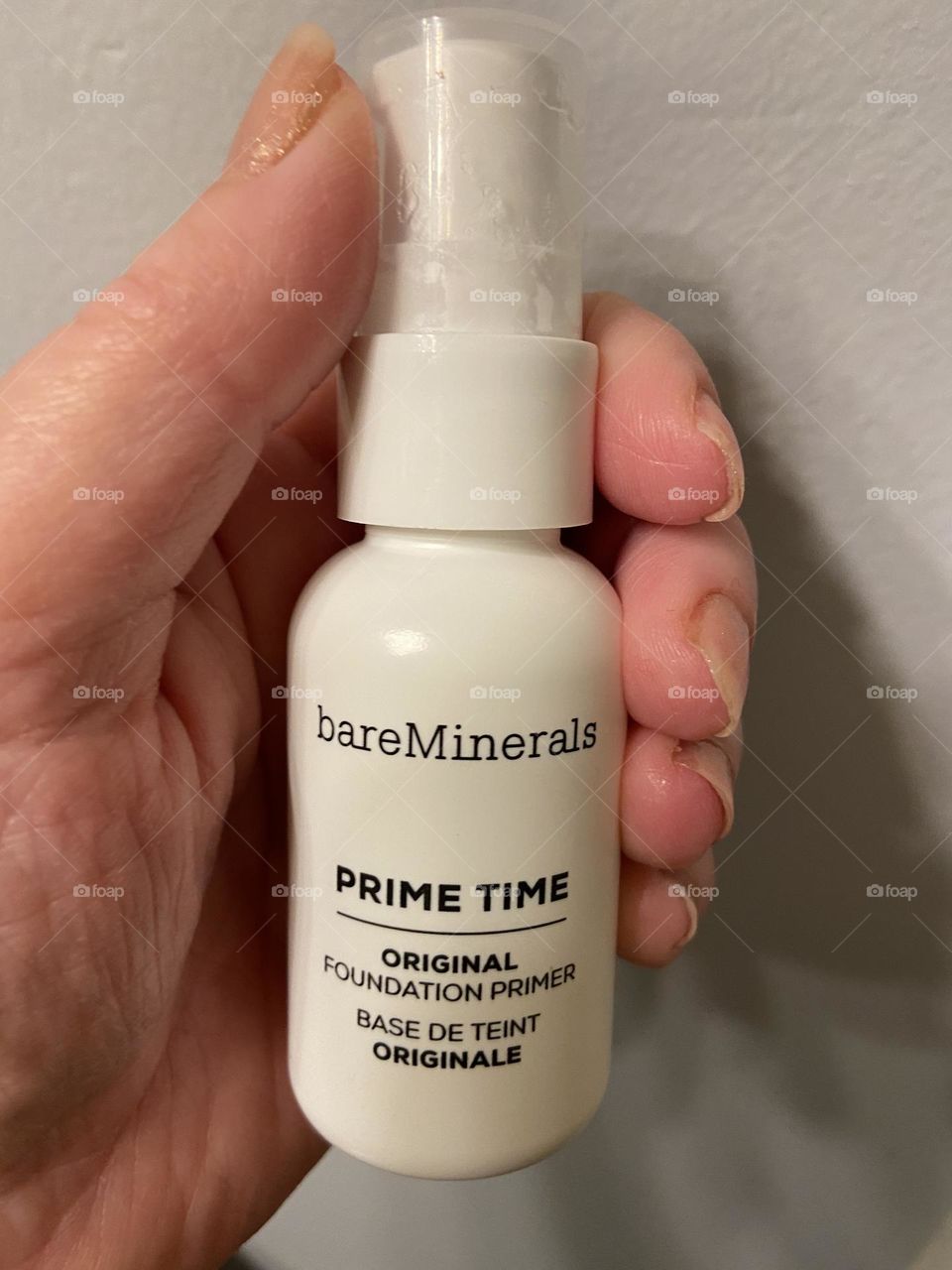 A woman’s hand holding Bare Minerals Prime Time Original Foundation Primer. I love this product because you only need a thin layer, and it goes on smooth and creates a good base to layer your foundation over. 