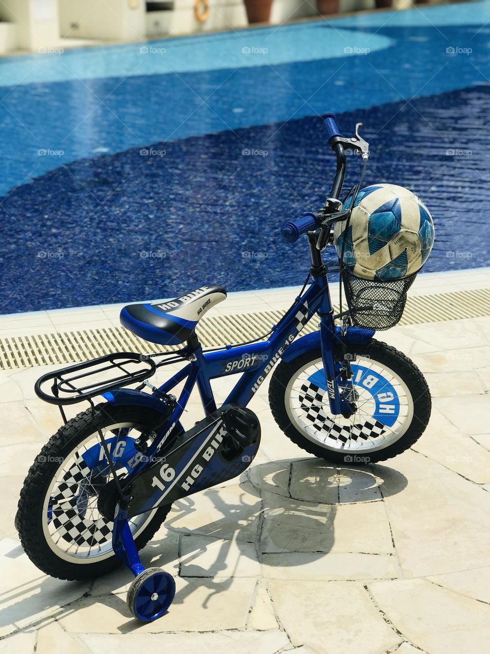 A blue by cycle with a blue football stand near blue colour water in swimming pool.