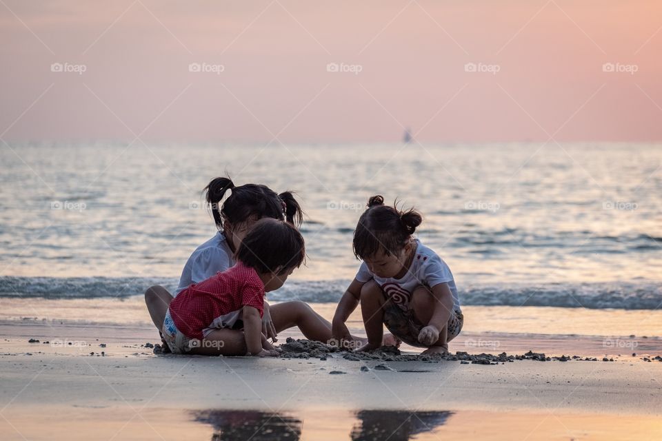 Three sisters sit on the beautiful beach to play together