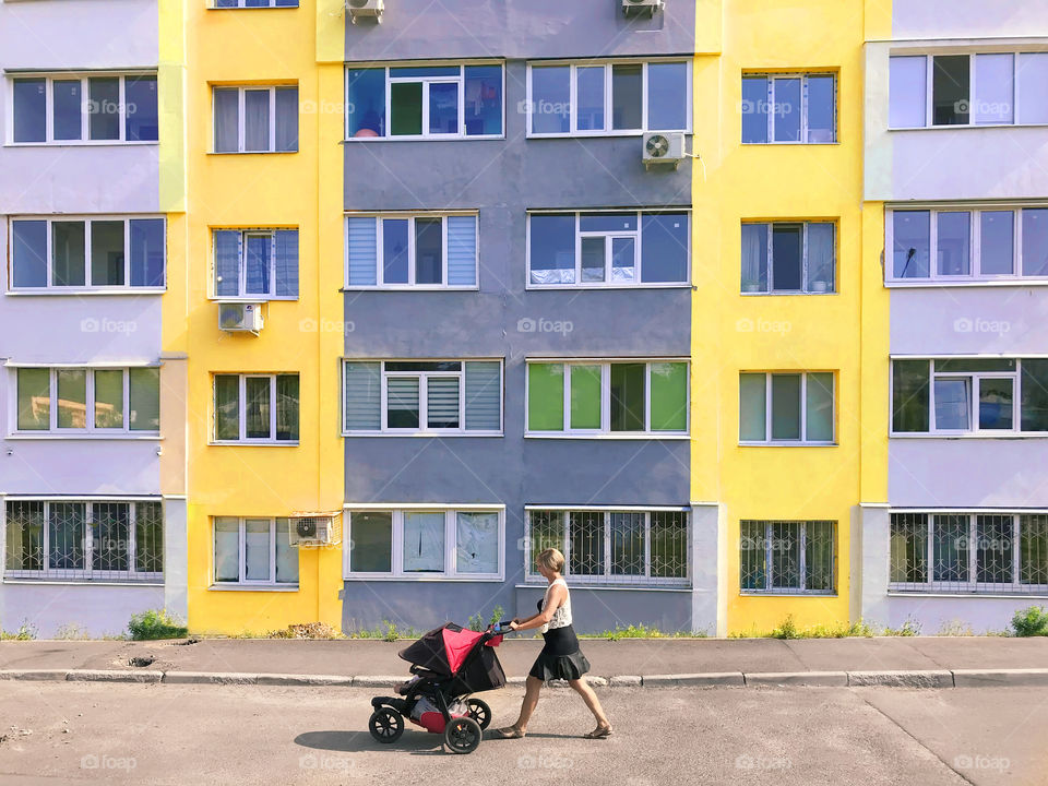 Young woman with a child walking in the city in front of colorful modern building 