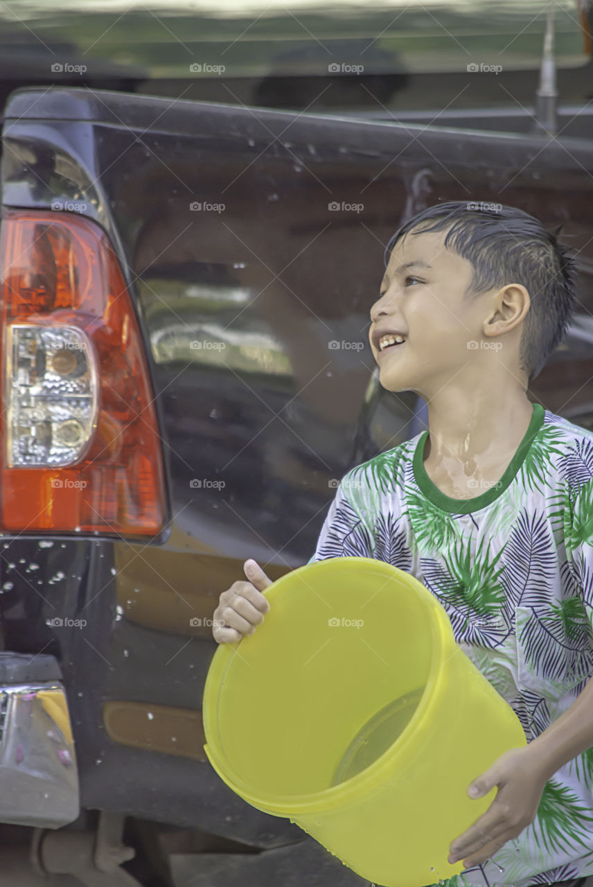 Asian boy holding Plastic bucket play Songkran festival or Thai new year in Thailand.