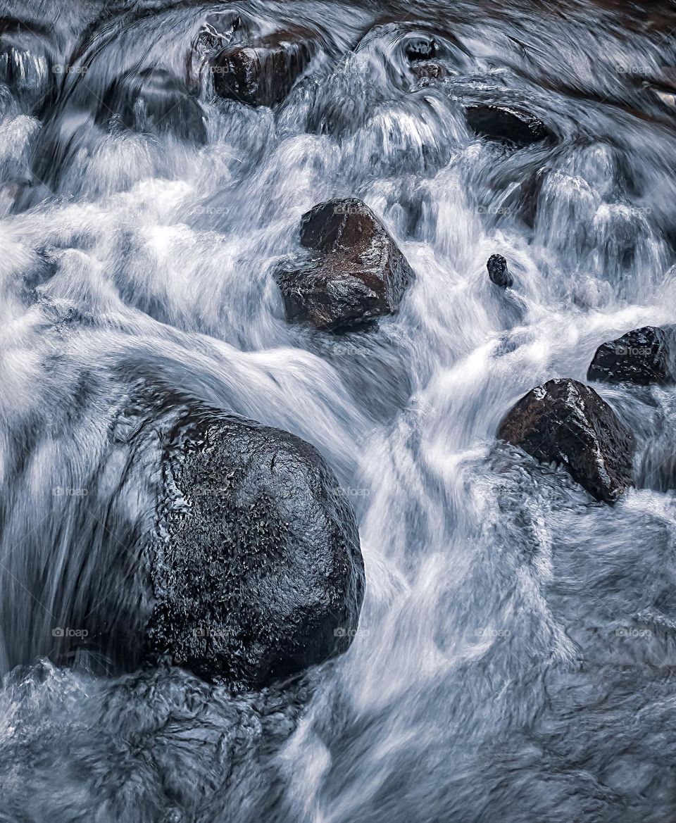 Fast flowing water over river rocks 