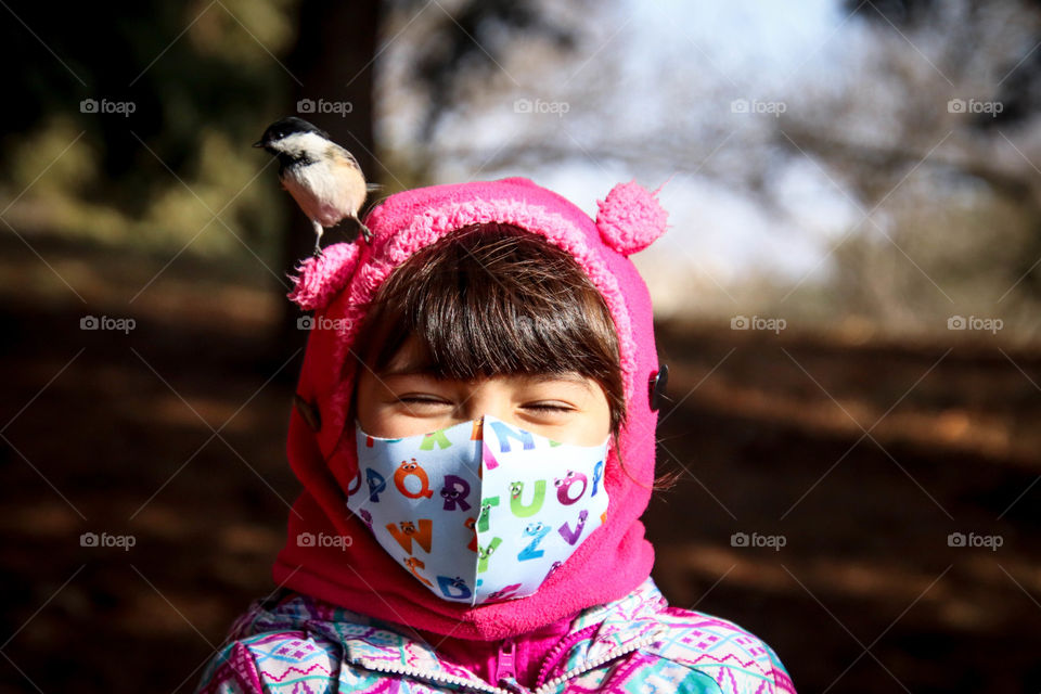 Cute little girl in face mask is having fun in a park