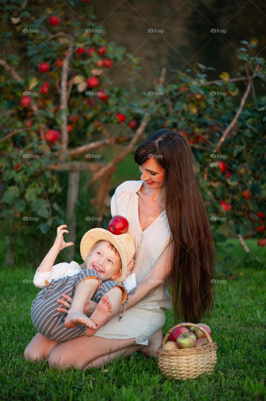 Mother and her little son on apple tree background in autumn evening