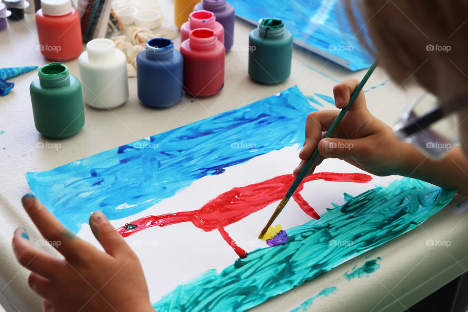 Child painting a dinosaur with watercolor