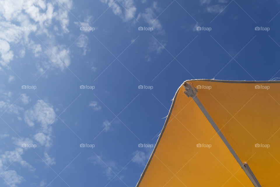 Clear summer sky view from under a yellow umbrella