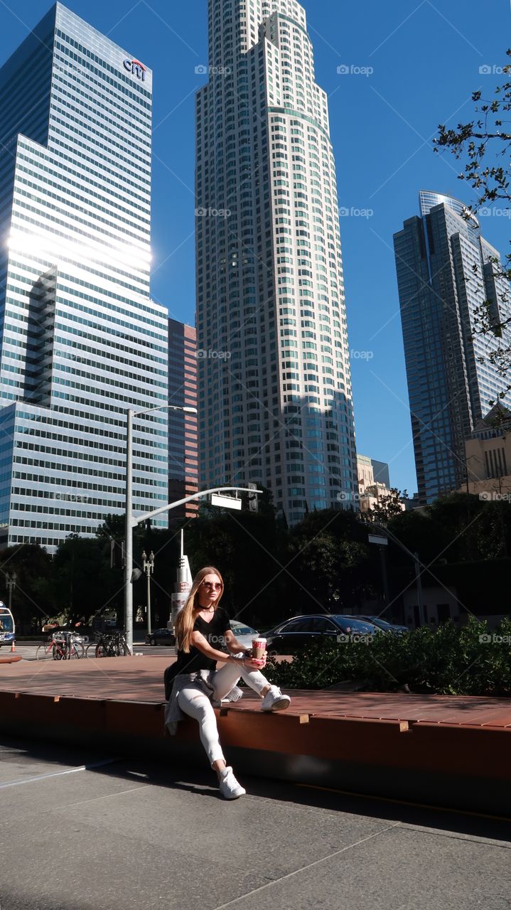 Young woman is sitting on the bench at Los Angeles downtown 