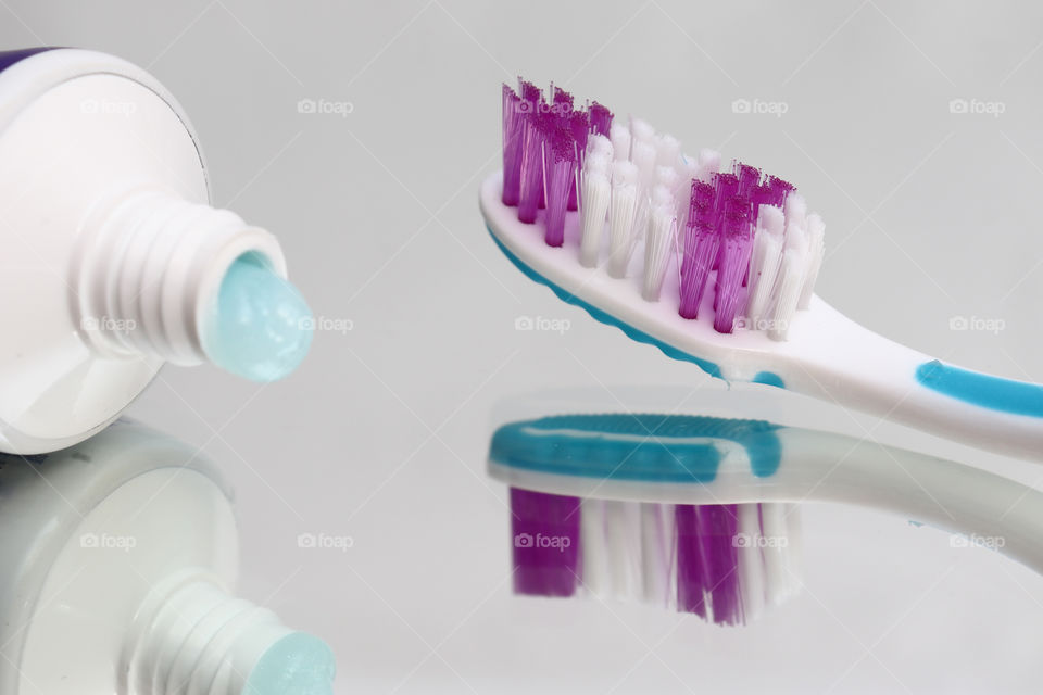 Toothbrushes and toothpaste on a mirror shelf. Oral hygiene products. Toothbrush - a device for cleaning teeth and gums massage.