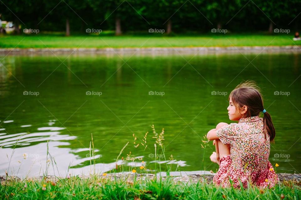 girl, sitting ,grass field one person,water ,lake, child childhood.