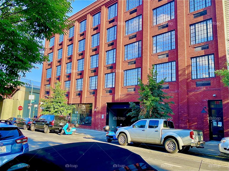 Warm colors on this large apartment complex building with an exposed brick facade that are glowing brightly during the golden hour of sunset in “Greenpoint”, Bklyn. 2022. Hypnotic Productions