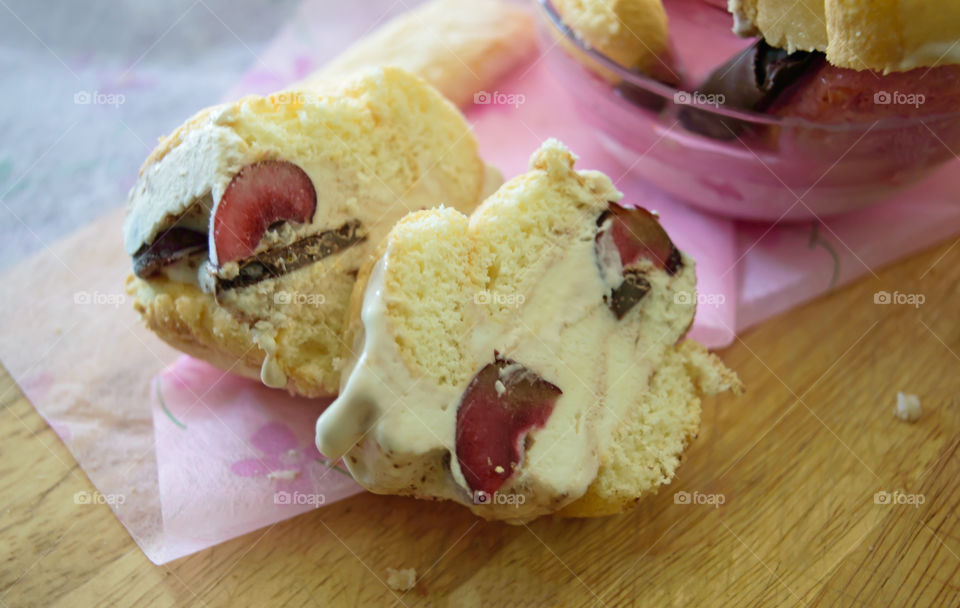 Homemade gourmet dessert  Ice cream treats closeup of vanilla ice cream sandwich sliced with cherry, dark chocolate and lady fingers on wood background with pink 