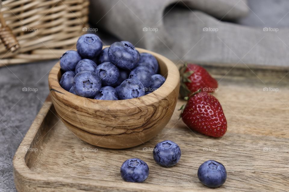 Blueberries and strawberries in wooden bowl 