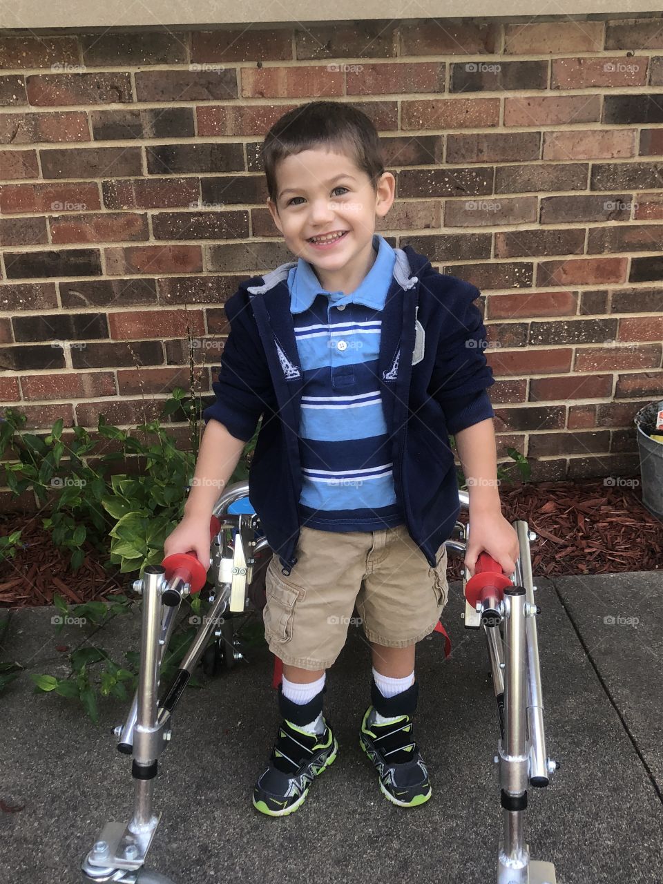 Special needs boy with walker smiling outside 