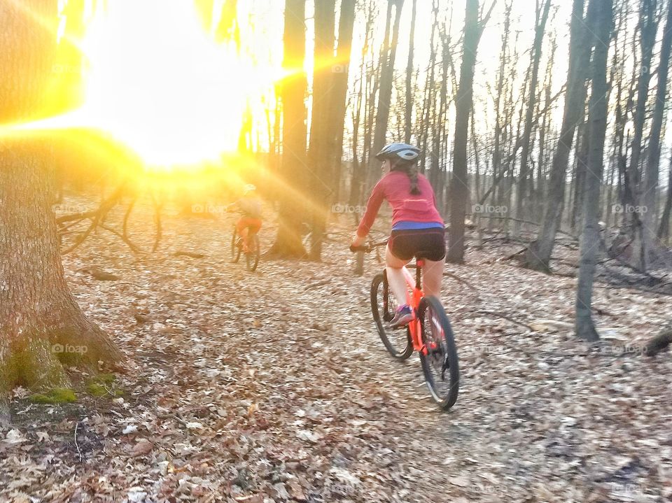 Beautiful woman bikes into sunset