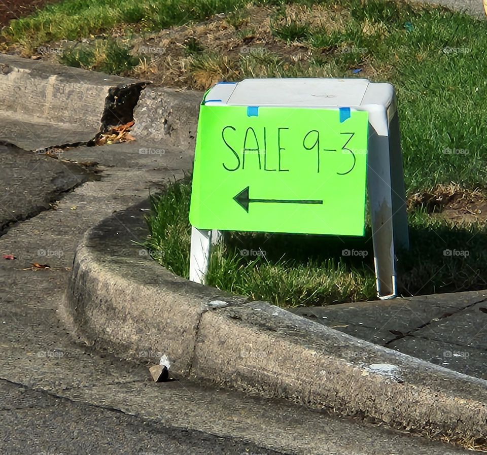 neon green weekend yard sale sign on street corner in suburban neighborhood