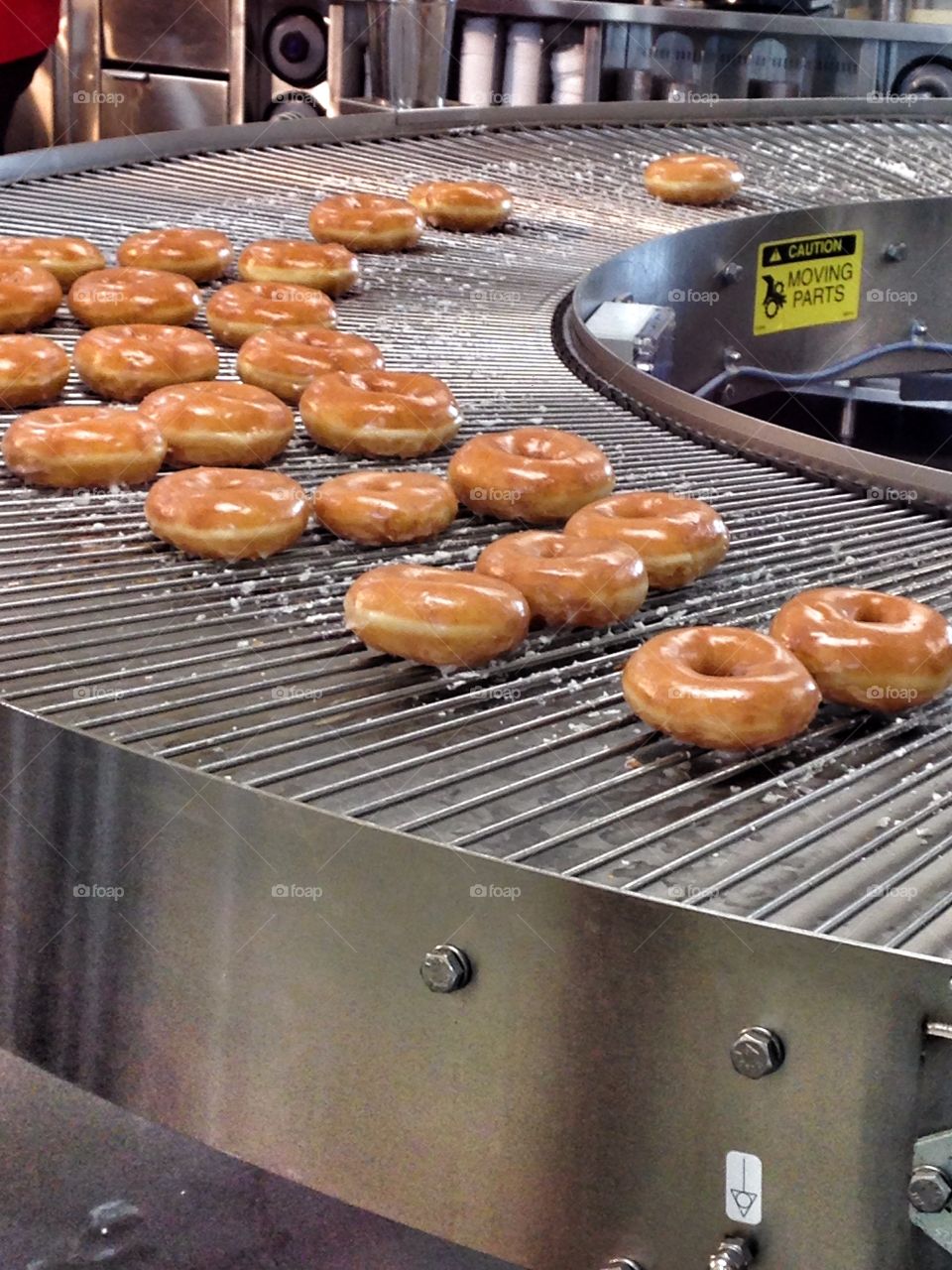 Time to make the donuts. Glazed donuts on baking conveyer belt at Krispy Kreme
