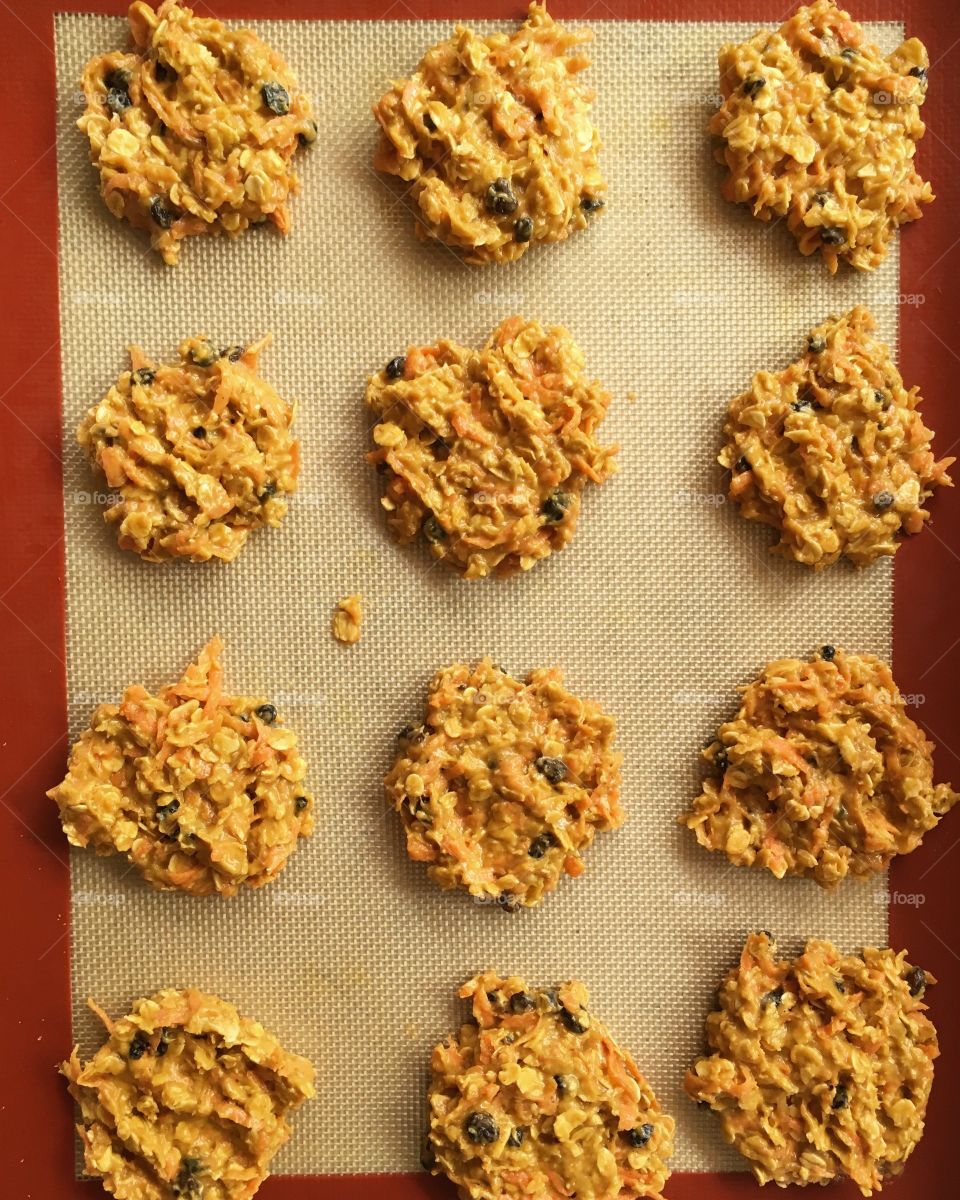 This is a photo is carrot cake cookies with currants and oats on a baking tray.