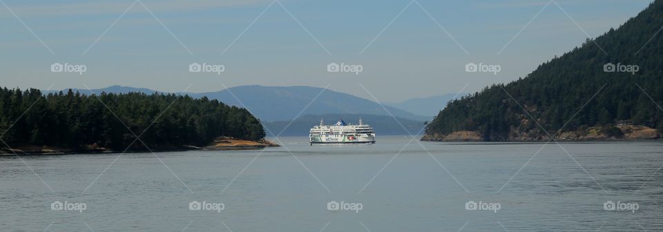 ferry passes between two island off the coast of British Columbia