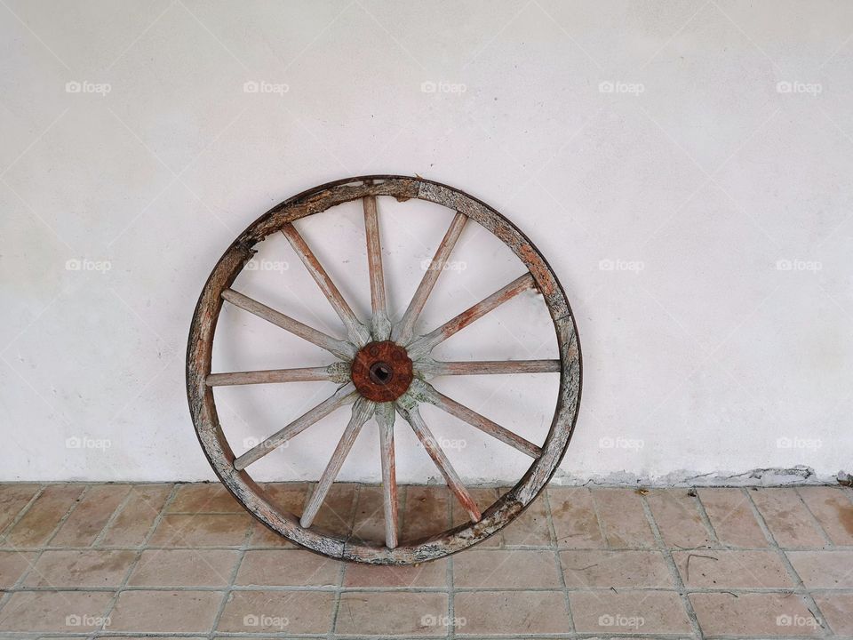 wooden wheel of an old wagon leaning against the wall