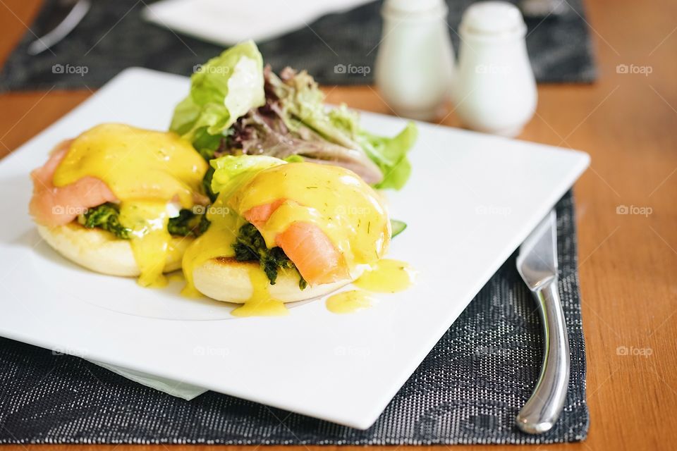 A delicious juicy eggs benedict with smoked salmon and spinach, topping with hollandaise sauce.