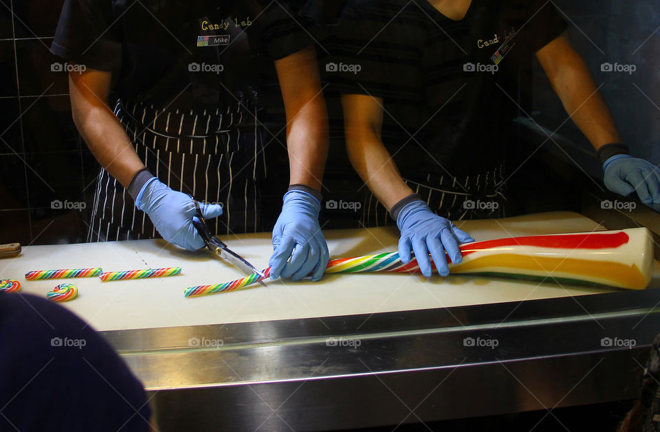 creating a candy lollypop. Workers in a local shop creating spiral shaped lollypops in shanghai, china.