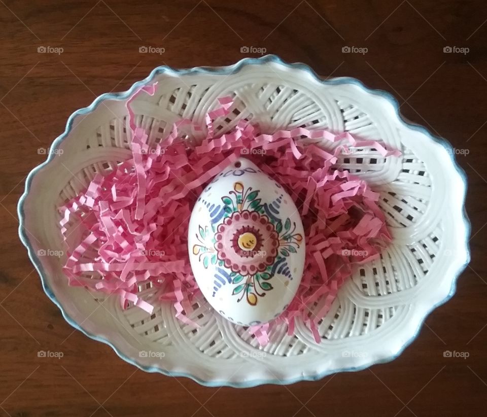 Close-up of a hand painted Czeck Easter egg resting on a cream and white Italian porcelain dish