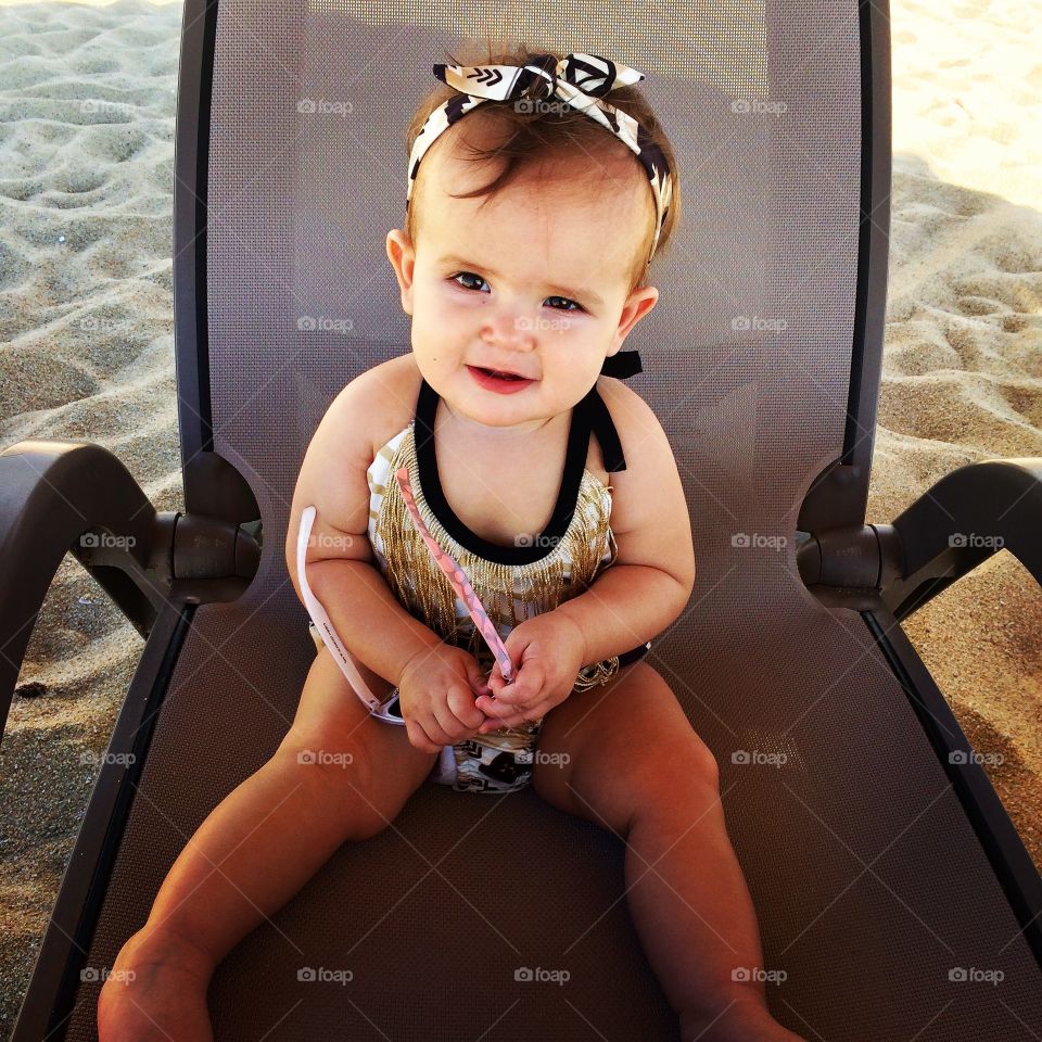 Little girl sitting on chair at beach