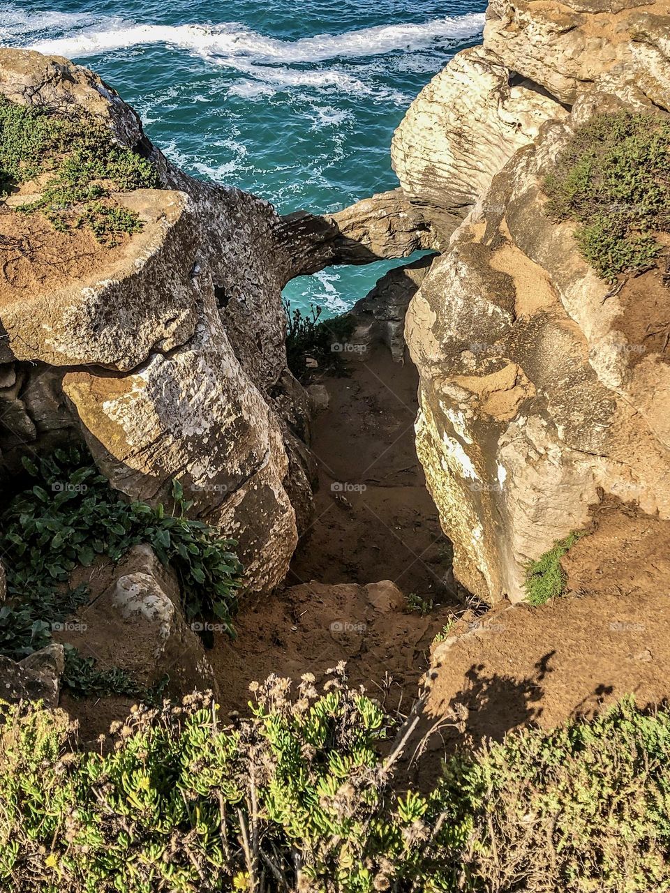 Rock formations along the Jurassic coast at Peniche allow glimpses of the Atlantic Ocean 