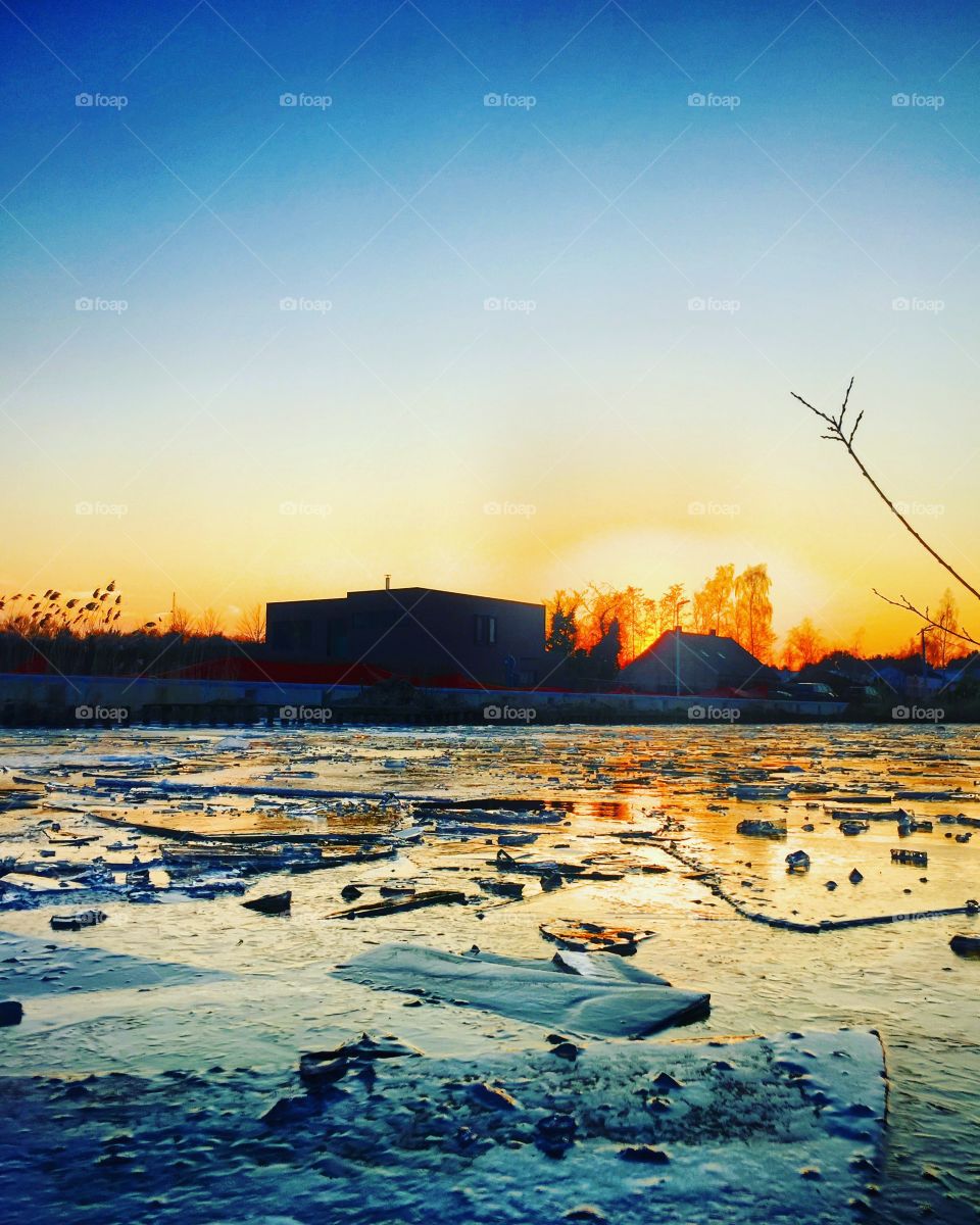 Broken pieces of ice on a frozen river or canal at sunrise or sunset in wintertime