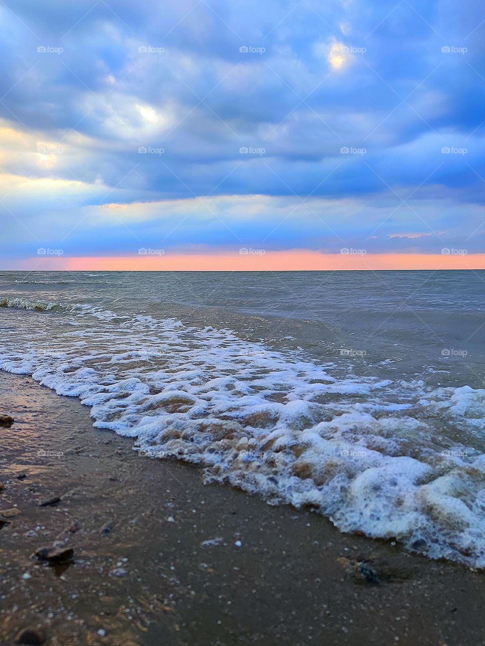 Sunset on the sea. The movement of the waves of the sea. The red stripe of sunset separates the stormy sea from the dark clouds of the sky