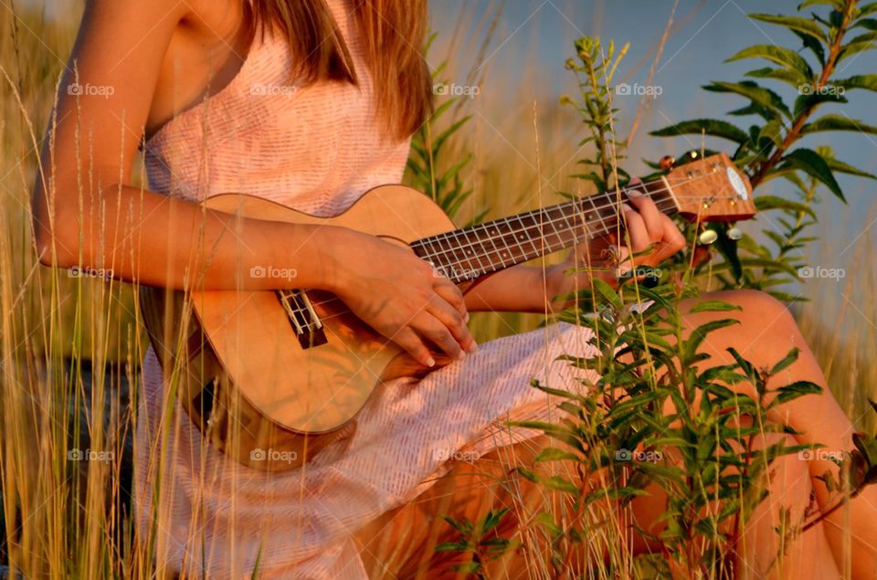 Woman playing guitar sitting outdoors
