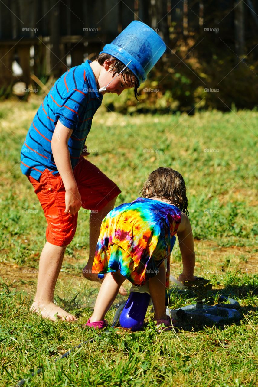 Kids Playing With A Sprinkler In Summer