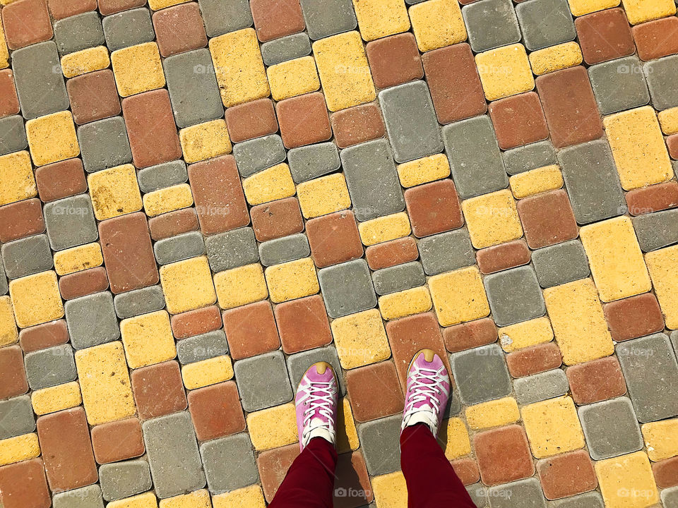 Feet standing on colorful geometric pattern of pavement 