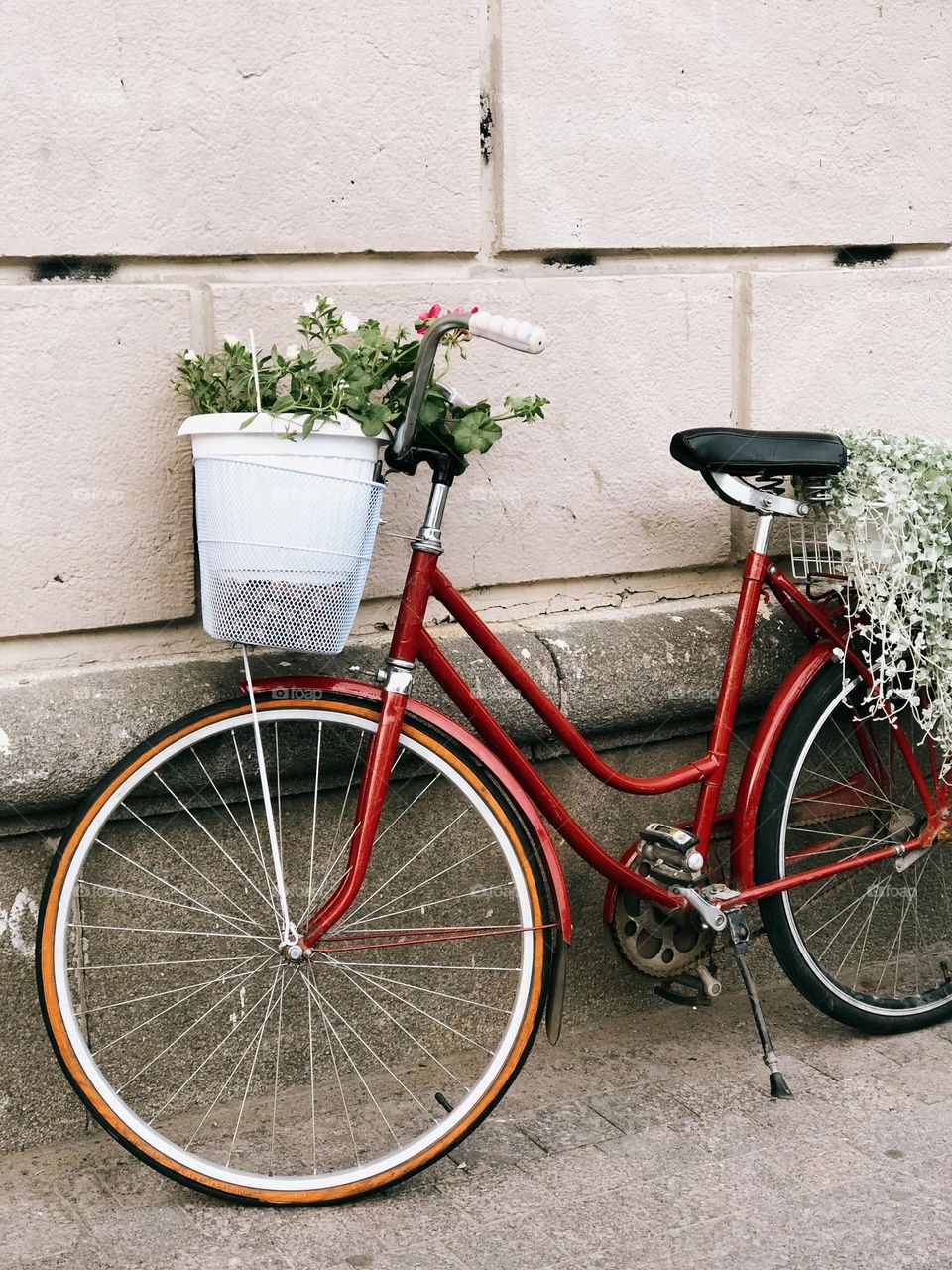 One lonely red bicycle with flowers on the street 