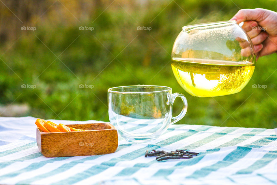 Hand holding teapot containing green tea