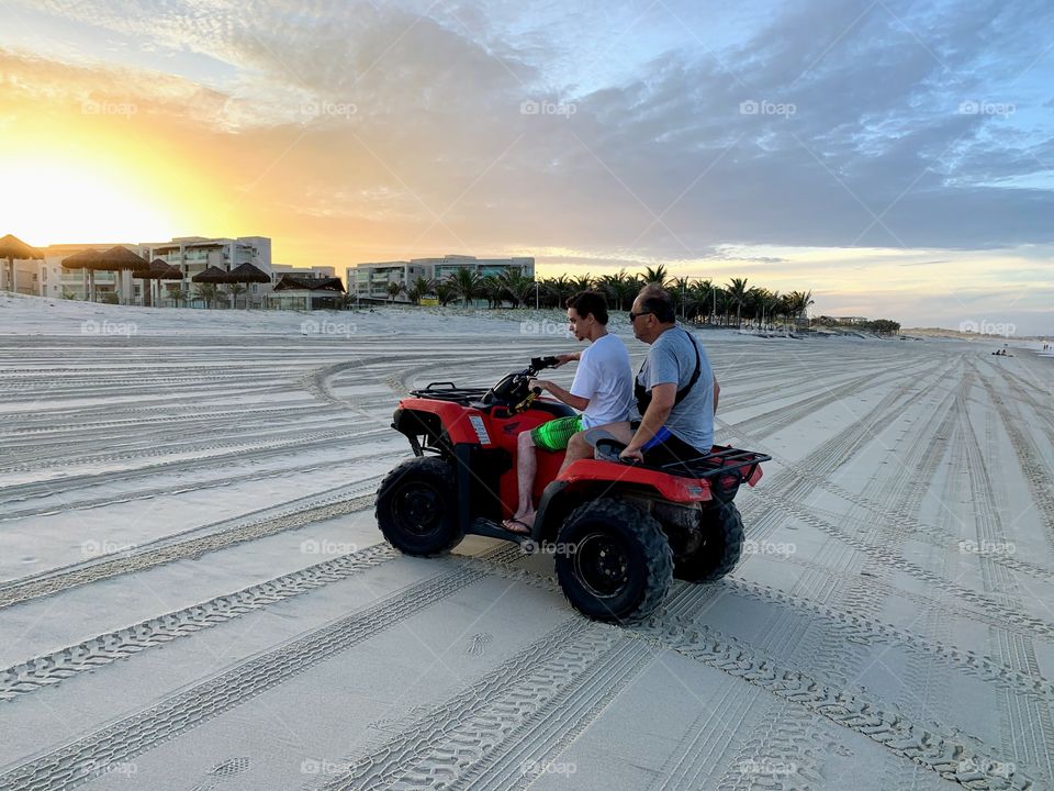 Father and son riding a quad on the beach in Aquiraz, Brazil